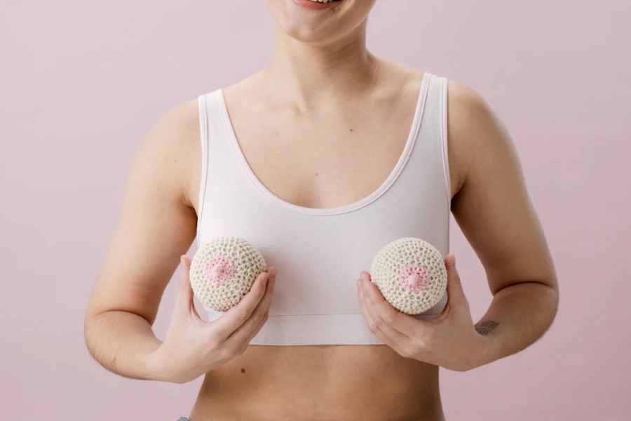 Frau hält zwei Brustprothesen an ihre Brust