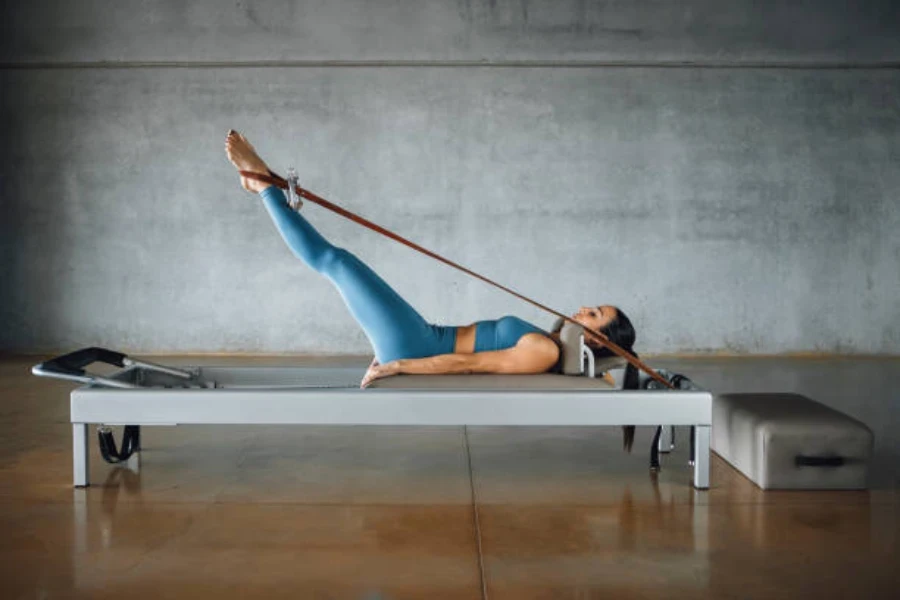 Mujer en la mesa usando banda de pilates para estirar las piernas