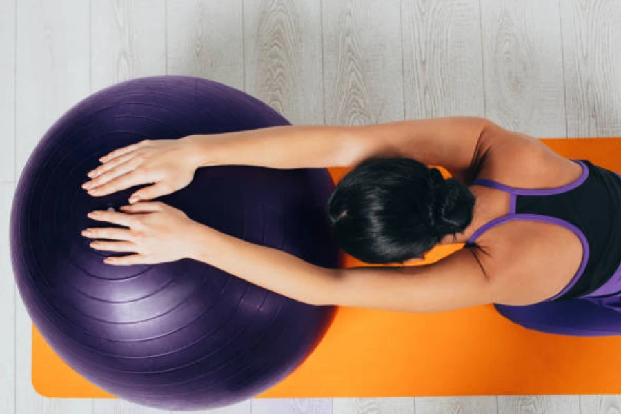 Mujer usando una gran pelota de fitness púrpura durante pilates