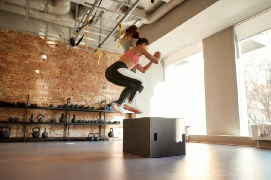 Femme utilisant un saut explosif pour atterrir sur une boîte plyo