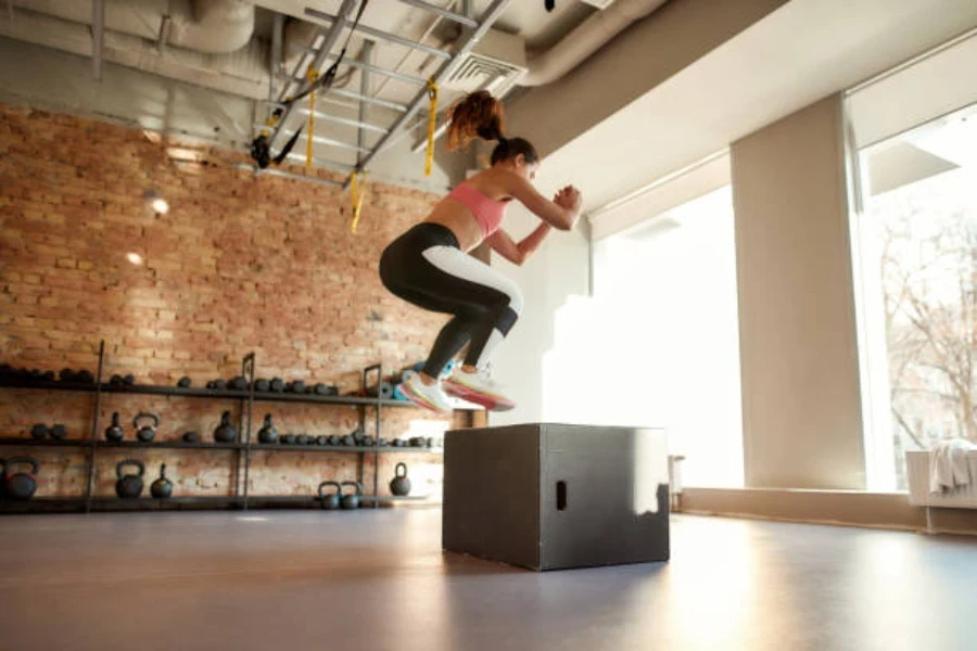 Mulher usando salto explosivo para pousar em plyo box