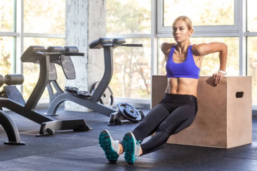 Donna che utilizza una scatola pliometrica in legno per eseguire push up dei tricipiti