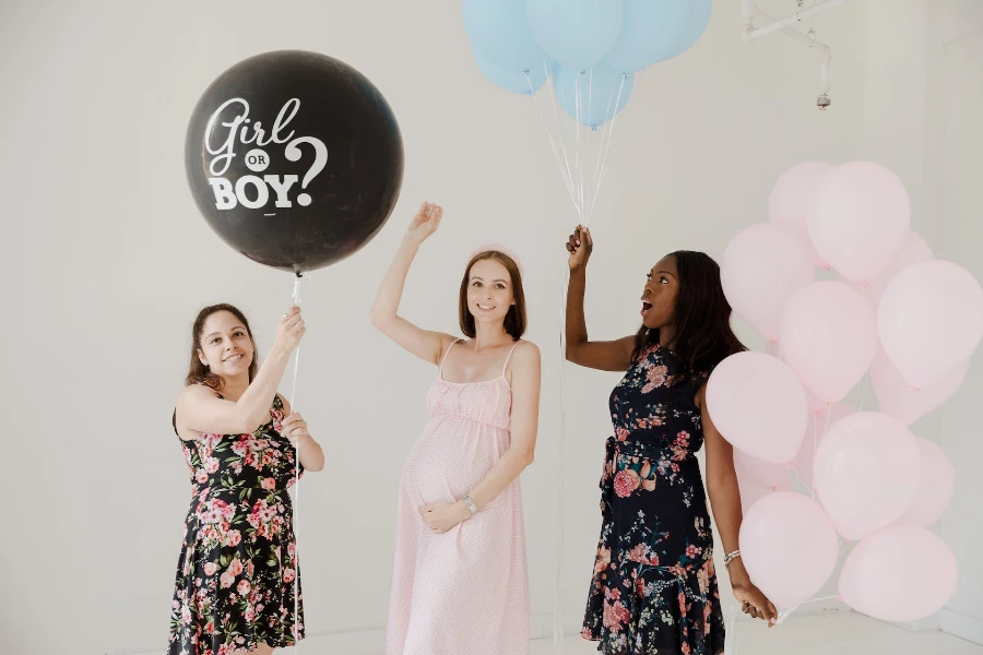 Women holding balloons for gender reveal party