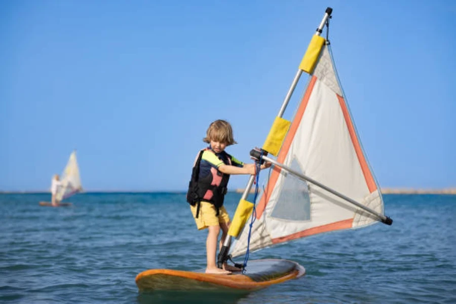 Young boy windsurfing while wearing specialized life jacket