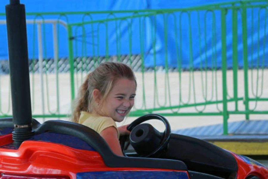 Young girl sitting inside ice bumper car holding steering wheel