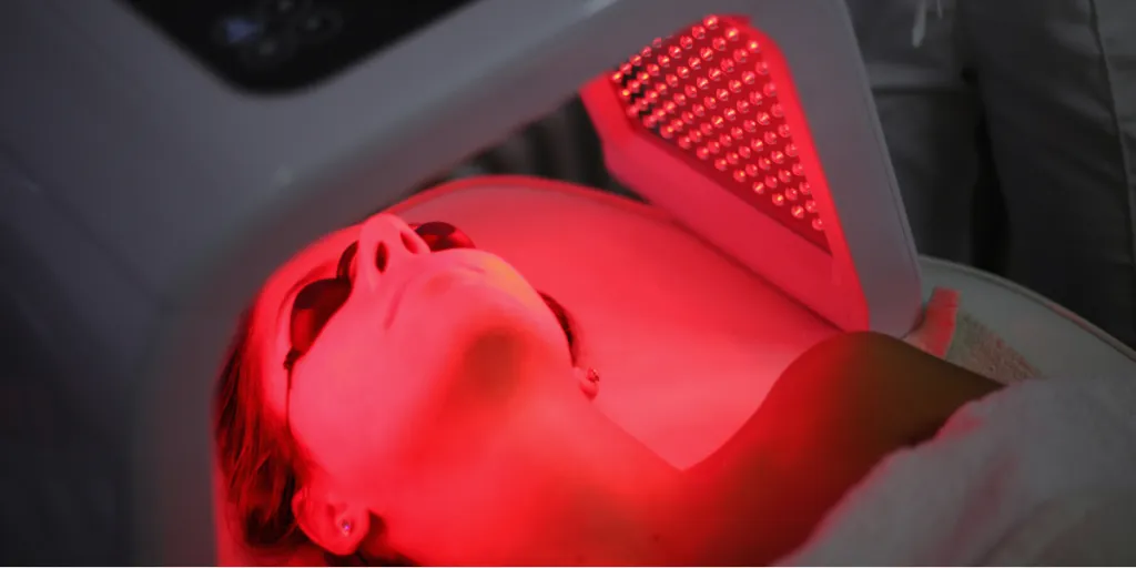 Young lady laying on a red light therapy machine