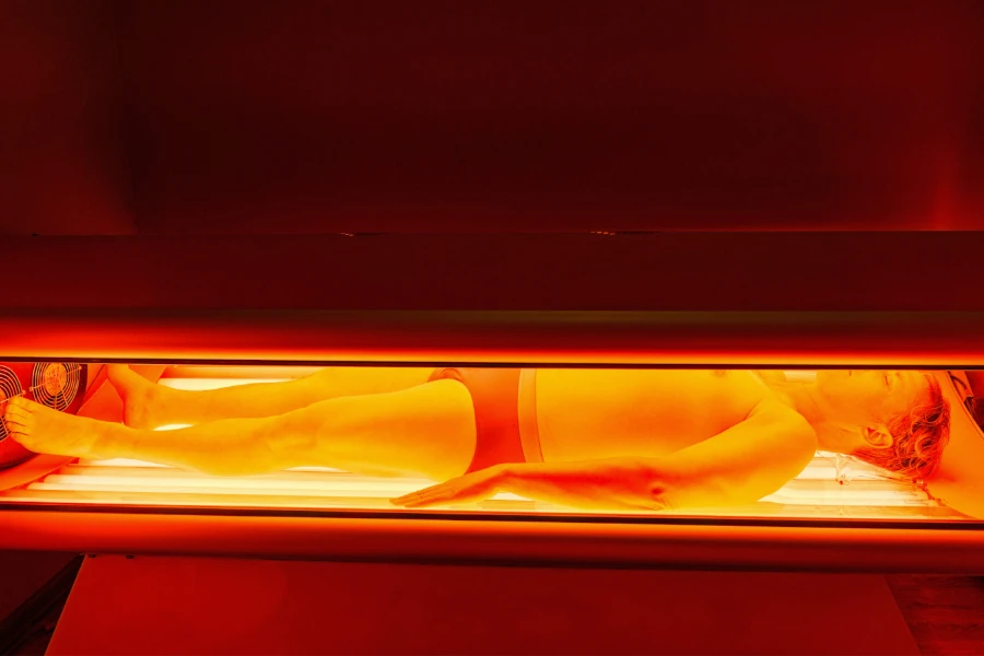 Jovem dentro de uma máquina de terapia de luz vermelha