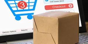 Cardboard Box On Laptop With Shopping Cart Displayed On Screen