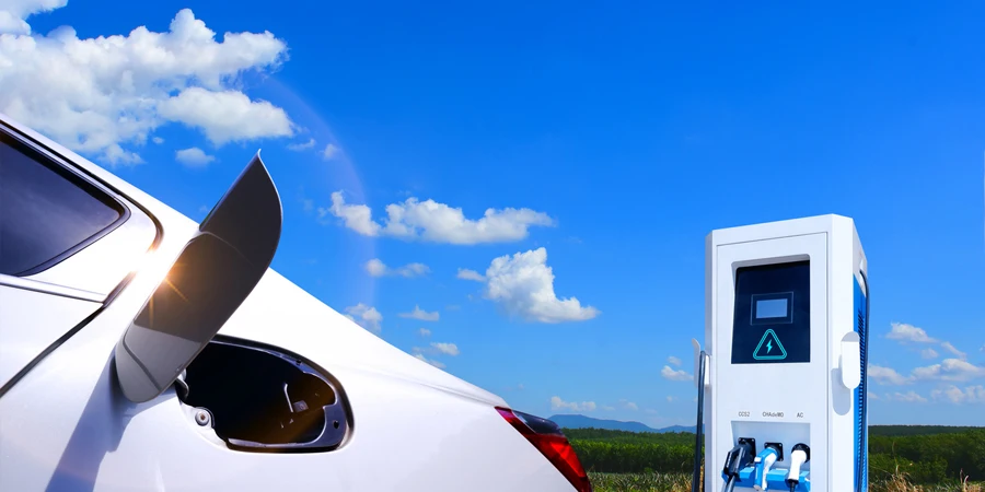 青い空と雲の背景を持つ電気自動車の充電ステーション