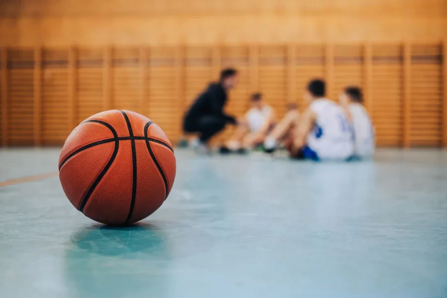 Indoor basketball on floor next to team sitting down
