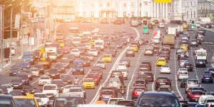 Lanes of a wide city street with lots of cars under the warm sunlight
