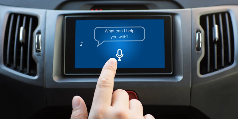 يد رجل تلمس نظام الوسائط المتعددة باستخدام المساعد الشخصي للتطبيق الذي يظهر على الشاشة في السيارة