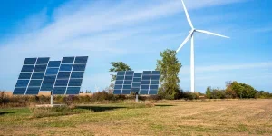 Solar panels and a wind turbine in a field on a clear autumn day