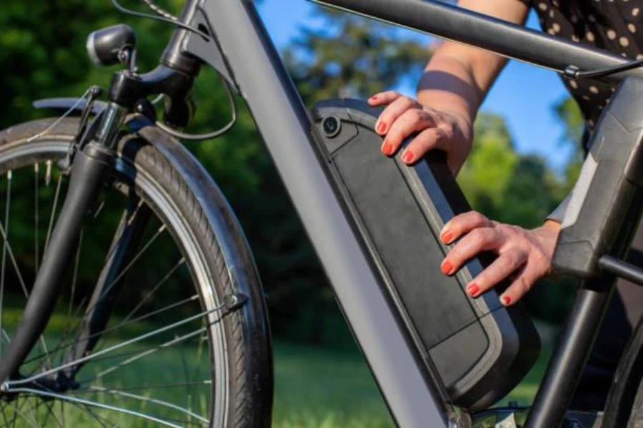 Una mujer ajustando la batería de su bicicleta eléctrica