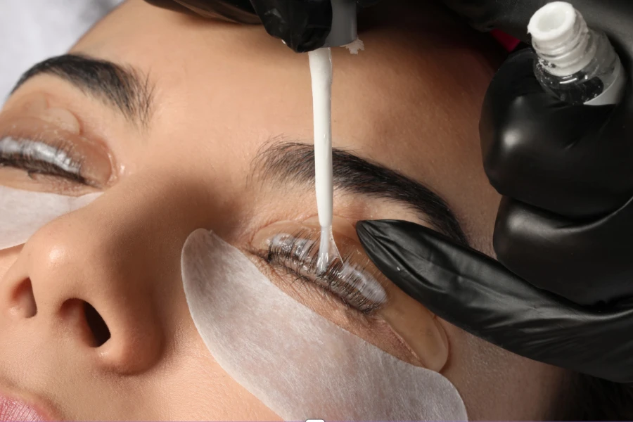 Aesthetician applying lash glue to a woman's lashes