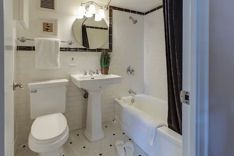 Cuarto de baño con cortina de ducha negra y azulejos blancos.