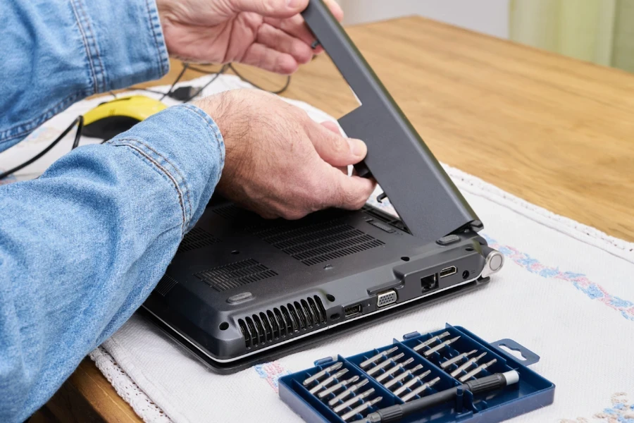 Technicien en informatique remplaçant la batterie d'un ordinateur portable