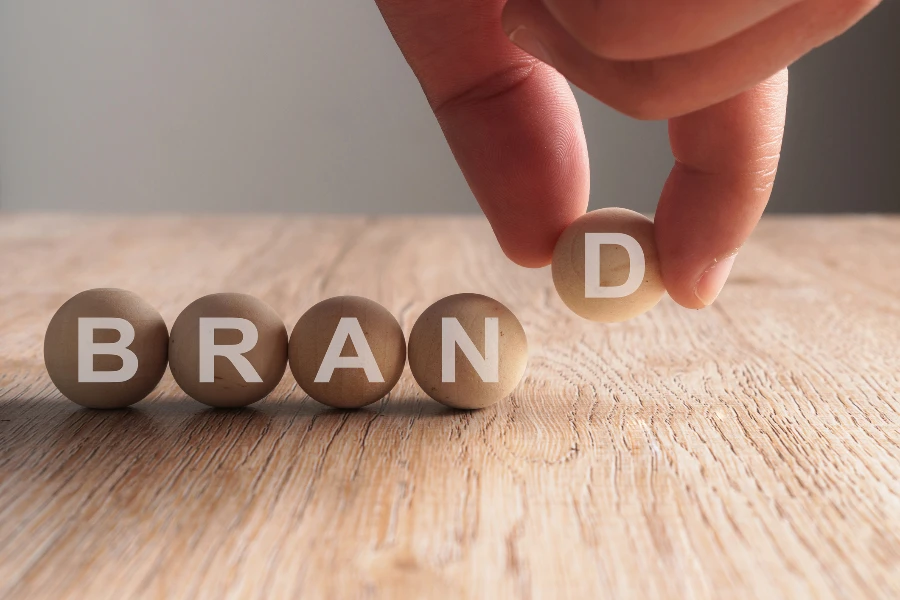 Hand putting final letter on the word BRAND