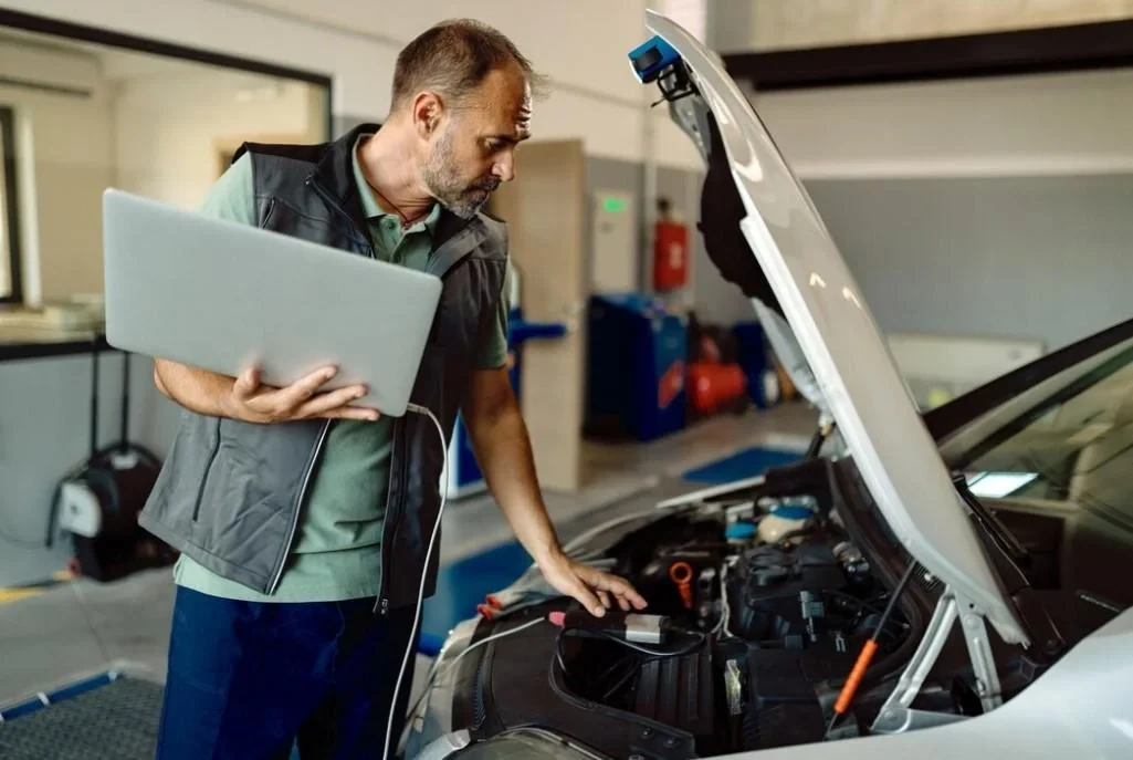 un ingeniero utiliza una computadora portátil para tuning de automóviles