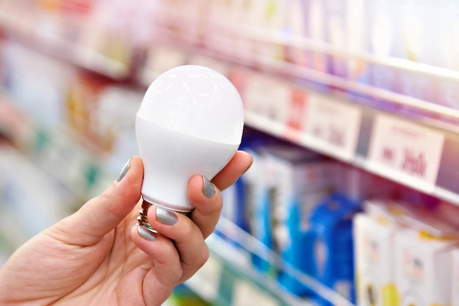 wanita memegang bola lampu LED di toko
