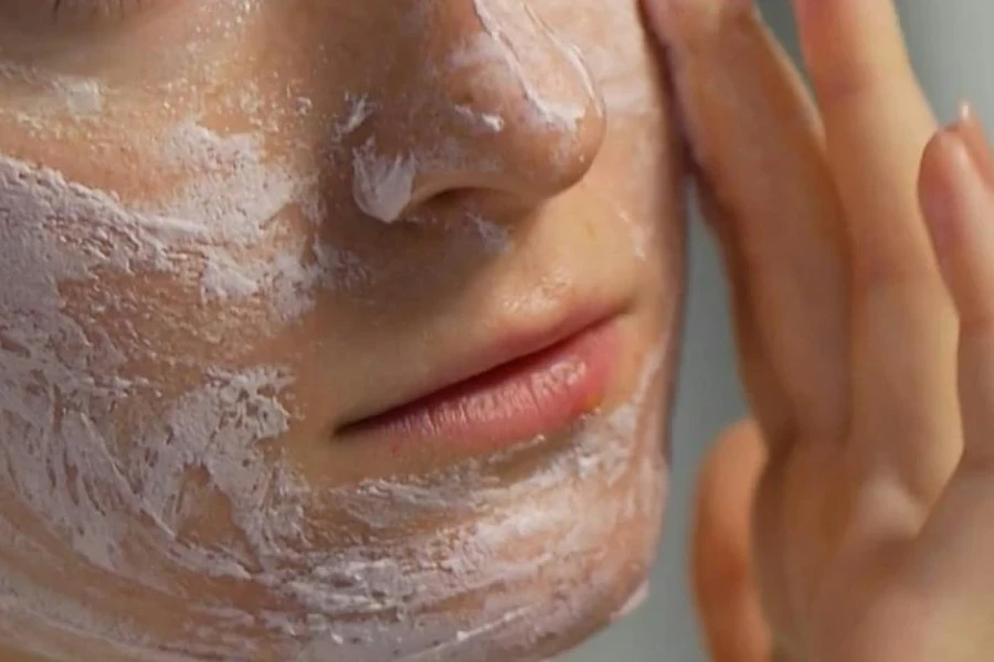 Señora frotando una crema facial blanca con los dedos