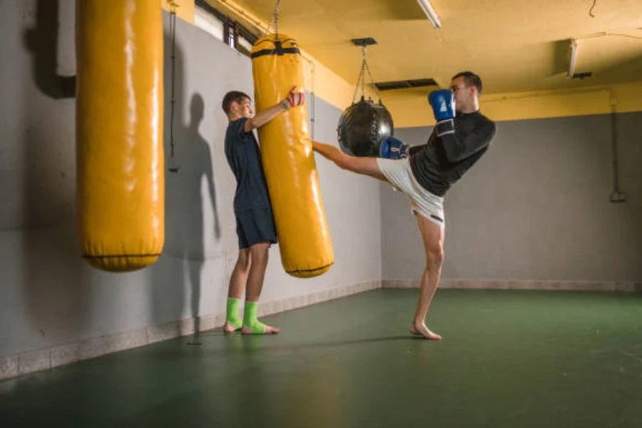 Man kicking yellow punching bag without shoes