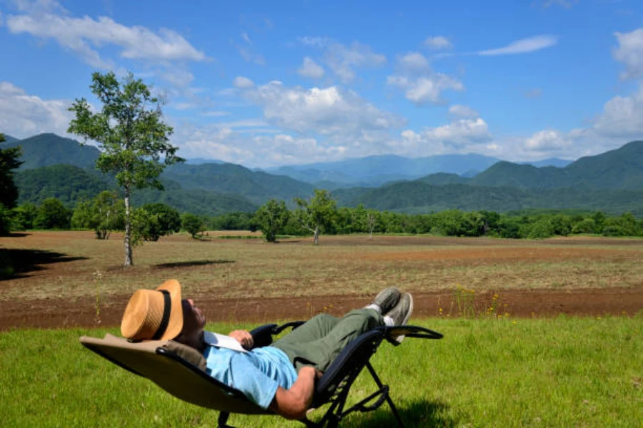 Pria berbaring di kursi gravitasi nol dengan pemandangan pegunungan