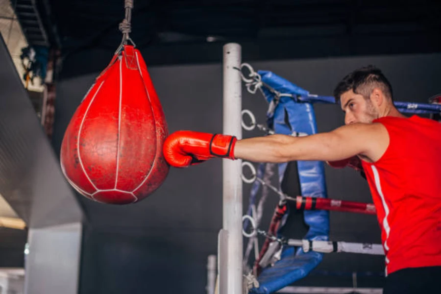 Man punching a red slip bag next to boxing ring