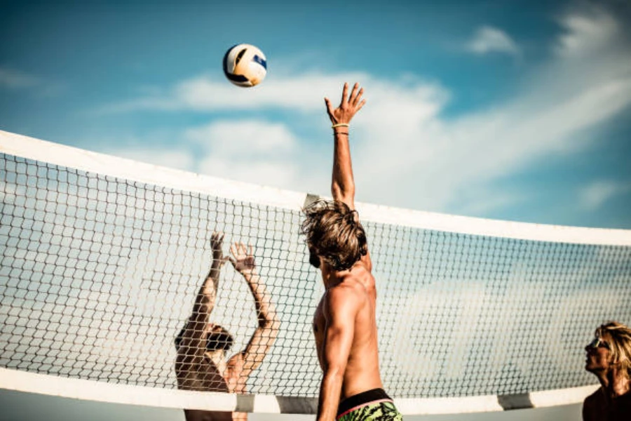 Güneşli bir günde plaj voleybolu oynayan erkekler
