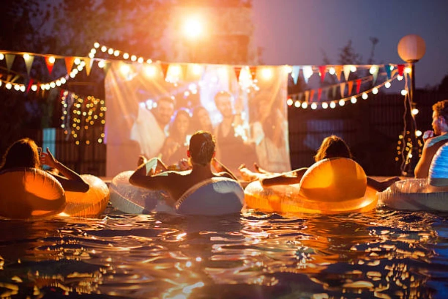 Gente viendo películas desde el interior de la piscina inflable para fiestas