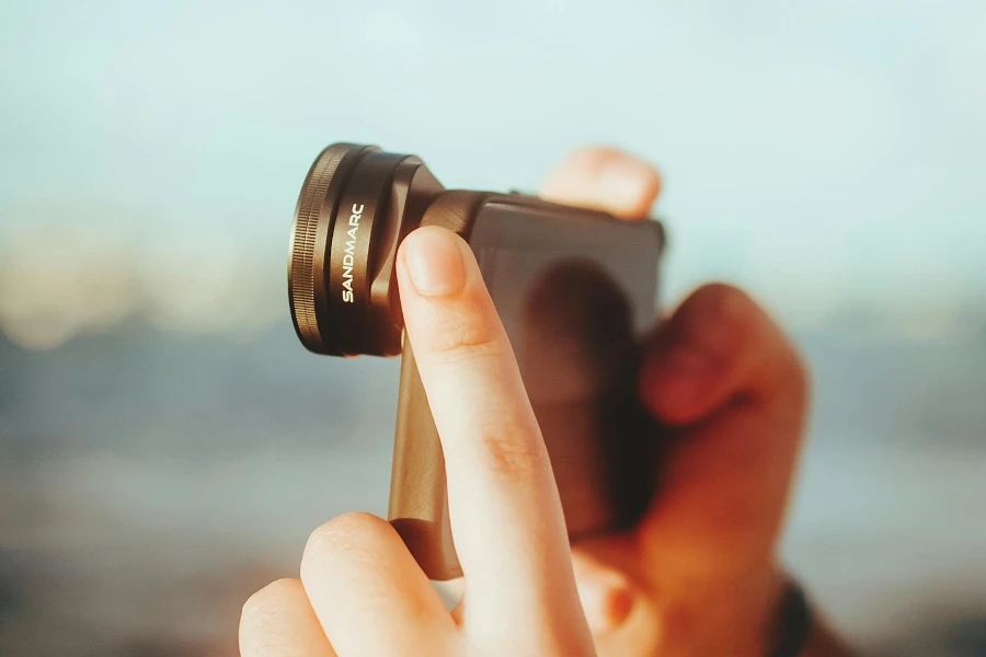Person taking a picture outdoors with a smartphone camera lens
