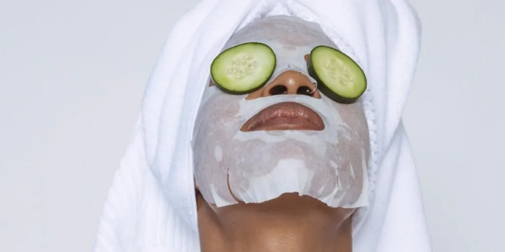 Person wearing a facial mask and cucumber slices