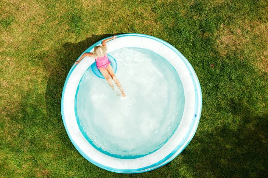 Piscina inflable redonda en el jardín con una mujer relajándose en el interior