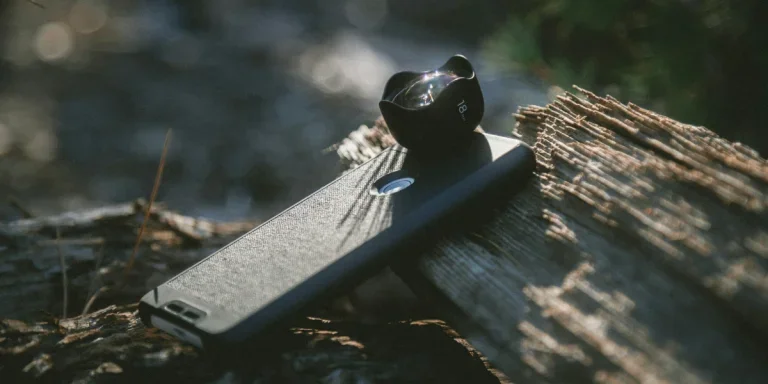 Smartphone with camera lens attached sitting on a log