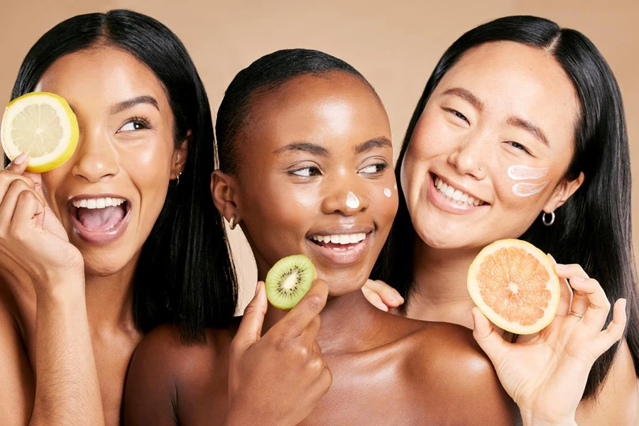 three women smiling while holding fruits