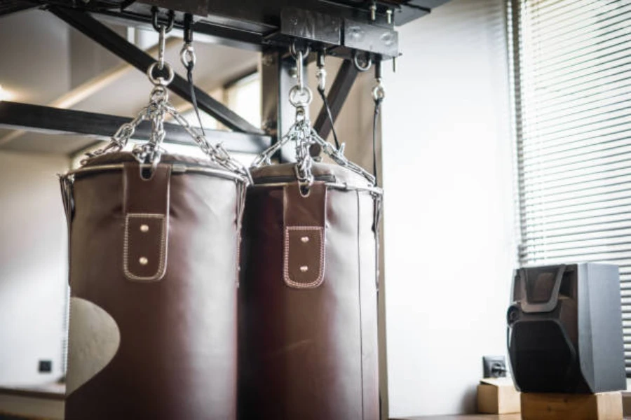 Two brown leather punching bags hung up side by side