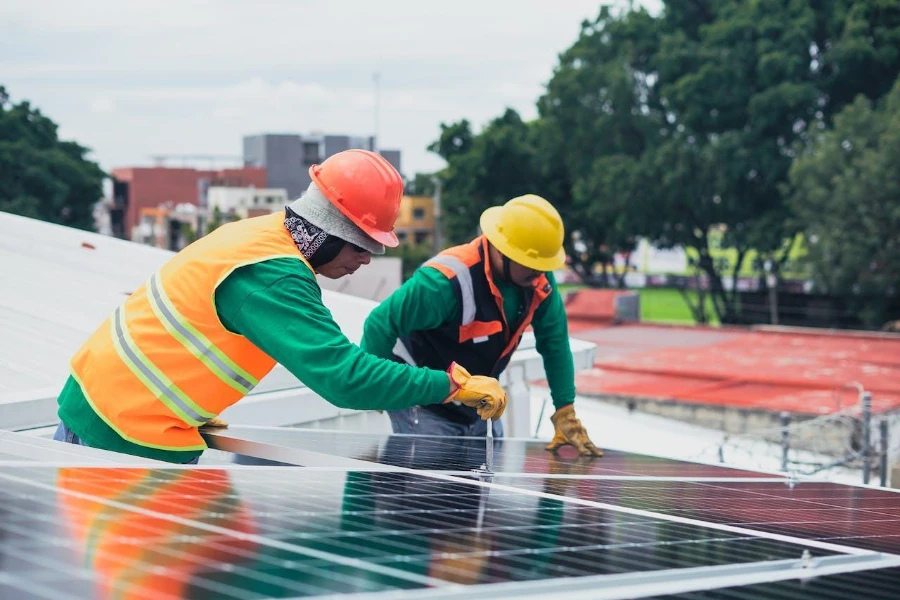 Two technicians repairing solar panels on a roof