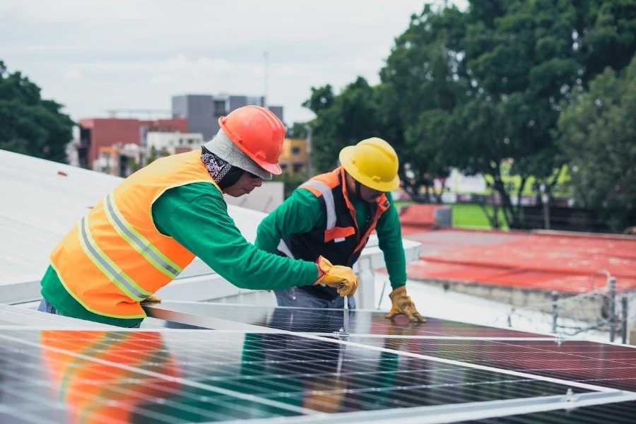 Dos técnicos reparando paneles solares en un tejado.