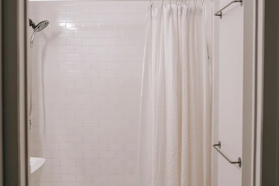 Белая текстурированная штора в ванной комнате, отделанной кафелем