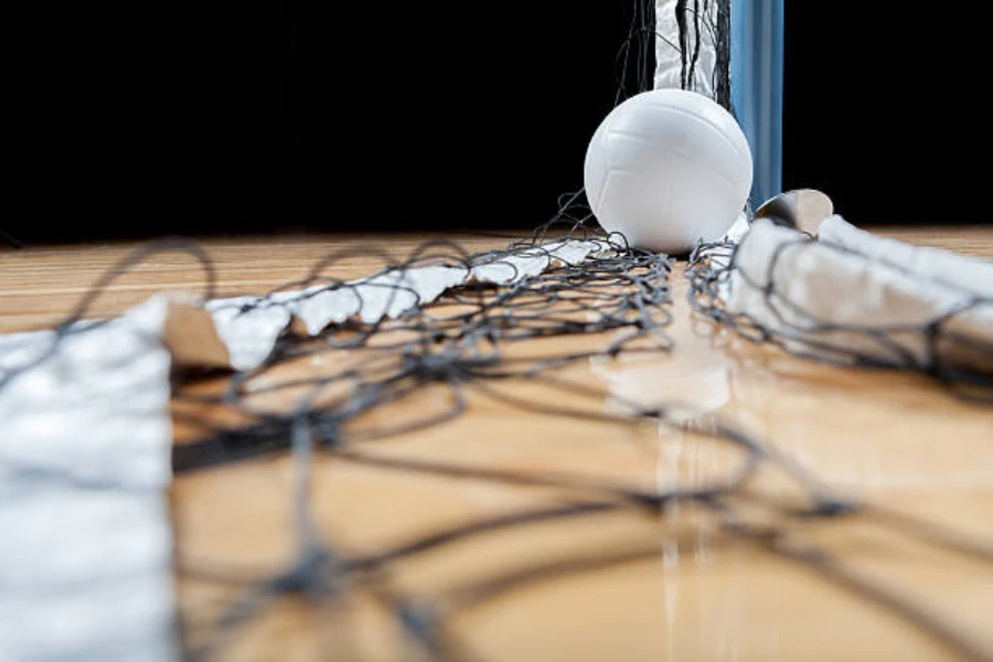 White volleyball sitting on tangled volleyball net on floor