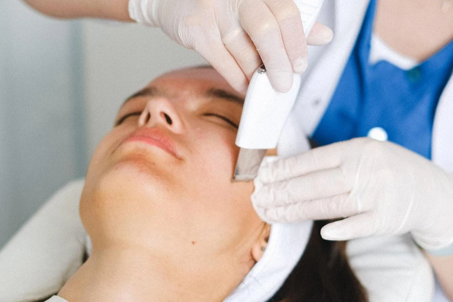 Frau lässt ihr Gesicht mit einem Ultraschall-Gesichtswäscher pflegen