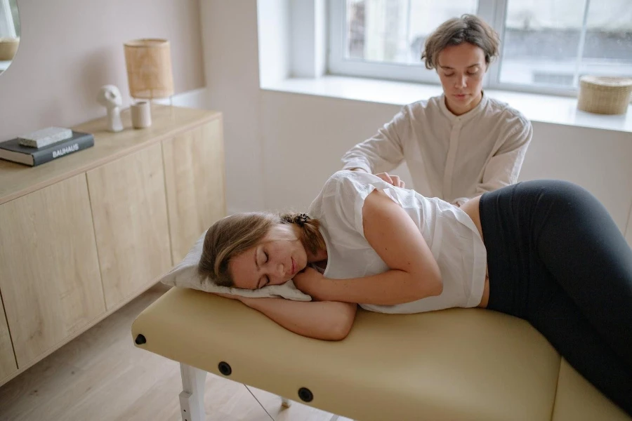Mujer acostada de lado sobre una camilla de masaje eléctrica