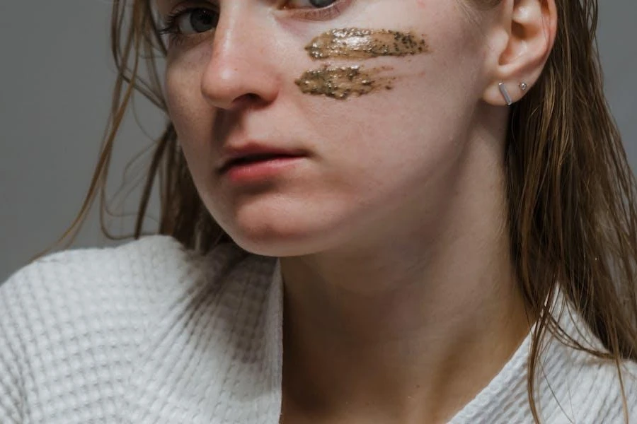 Mujer posando con vetas de exfoliante facial en la cara