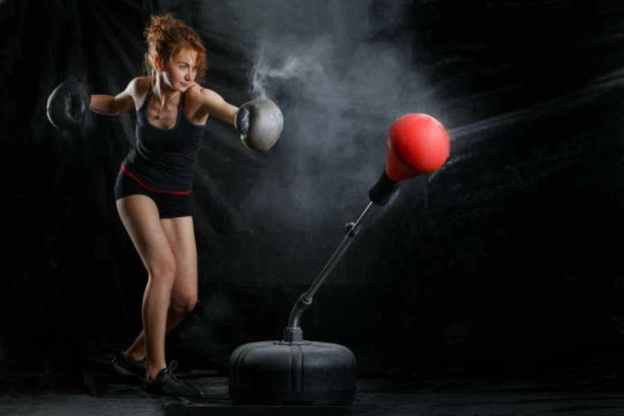 Femme frappant un sac de boxe autoportant rouge et noir