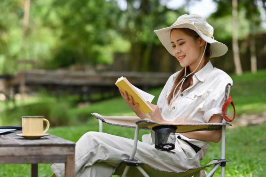 本を読みながらキャンプ用の椅子に座る女性