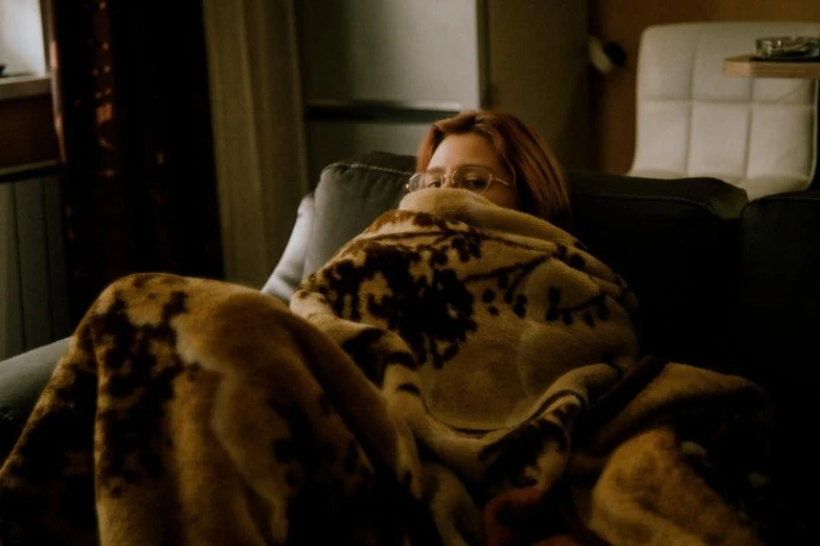 Woman sitting under a large brown faux fur throw
