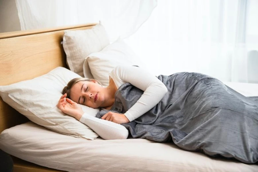 Woman sleeping under a gray throw blanket