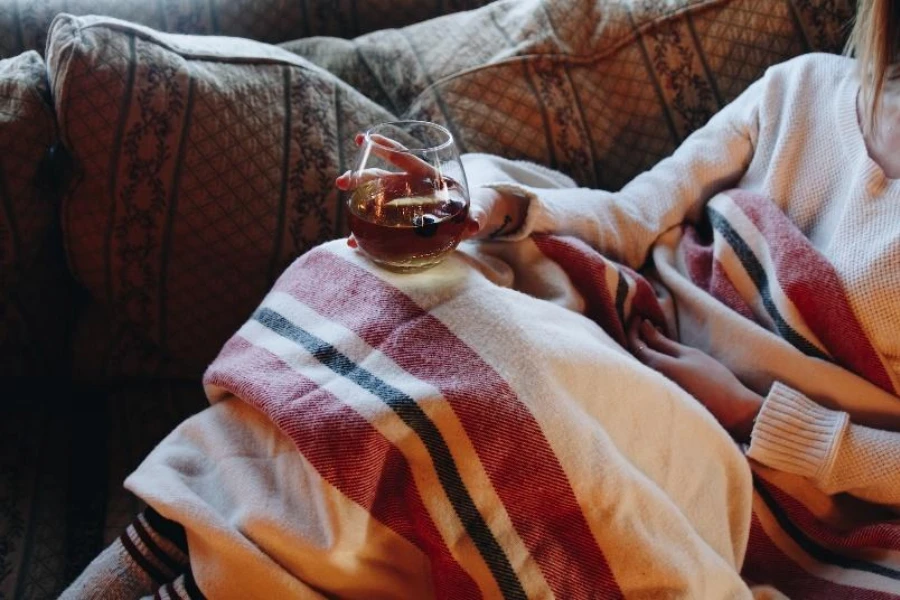 Женщина под полосатым одеялом на диване