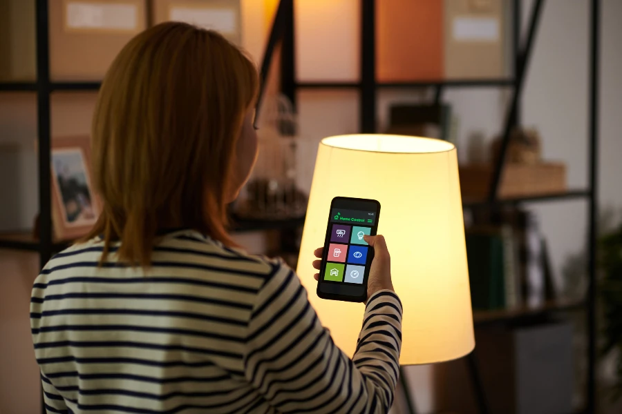 mulher usando aplicativo de smartphone para controlar lâmpadas inteligentes