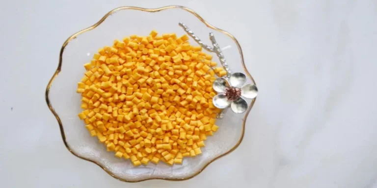 A clear glass plate with gold trim containing a heap of small, diced yellow cubes